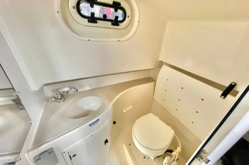  Yacht Photos Pics 2004 Pursuit 2870 Walkaround boat bathroom with sink, toilet, and porthole window.