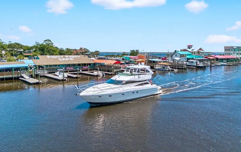  Yacht Photos Pics 2004 Neptunus 56 Flybridge yacht cruising near colorful waterfront cafes.