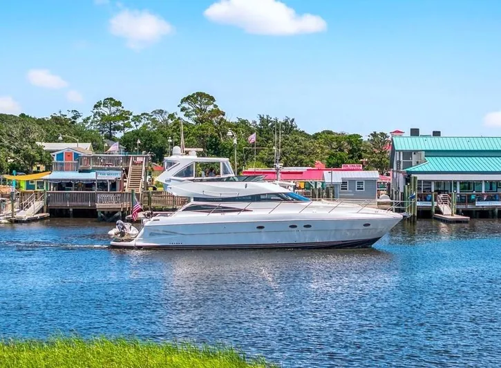  Yacht Photos Pics 2004 Neptunus 56 Flybridge yacht cruising near colorful waterfront buildings.