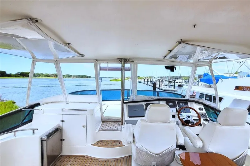  Yacht Photos Pics Flybridge view of 2004 Neptunus 56 yacht, featuring helm and seating, overlooking marina.