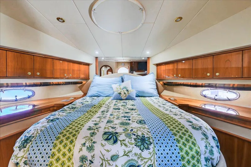  Yacht Photos Pics Luxurious 2004 Neptunus 56 Flybridge yacht bedroom with elegant bedding and wood cabinetry.