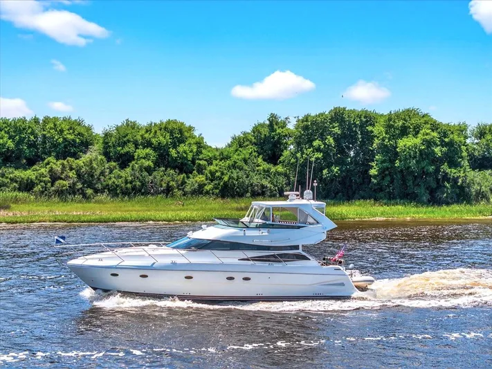  Yacht Photos Pics 2004 Neptunus 56 Flybridge yacht cruising on a river with lush green trees.