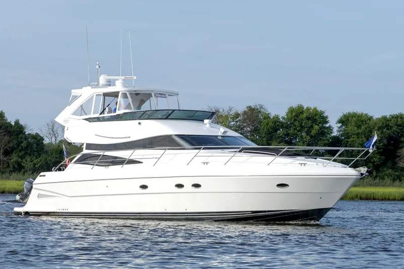  Yacht Photos Pics 2004 Neptunus 56 Flybridge yacht cruising on a calm river with lush greenery.