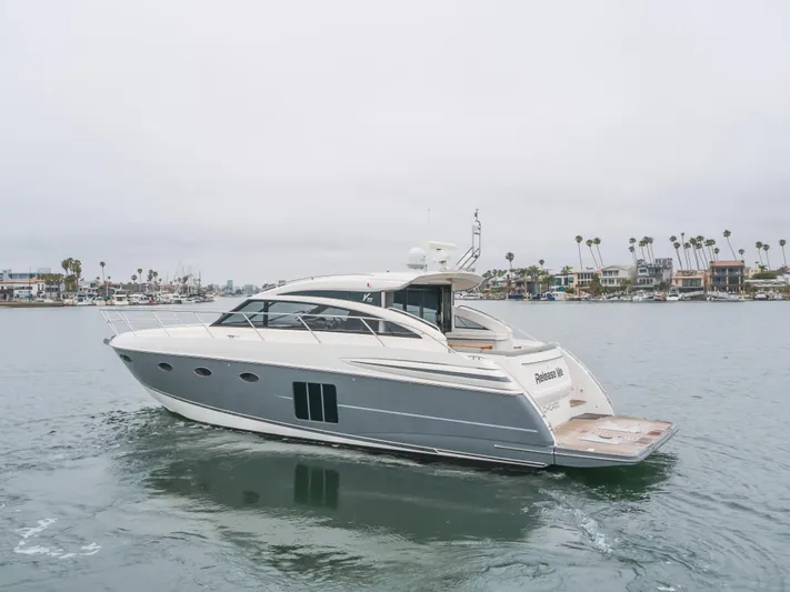 Release Me Yacht Photos Pics 2013 Princess V52 yacht cruising in a calm harbor with coastal homes in the background.