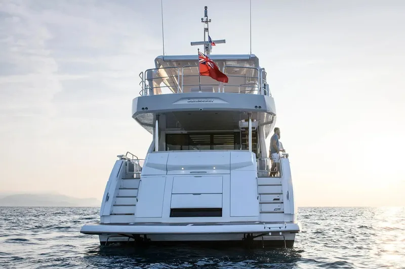  Yacht Photos Pics 2023 Sunseeker 76 Yacht on calm sea, rear view with flag.