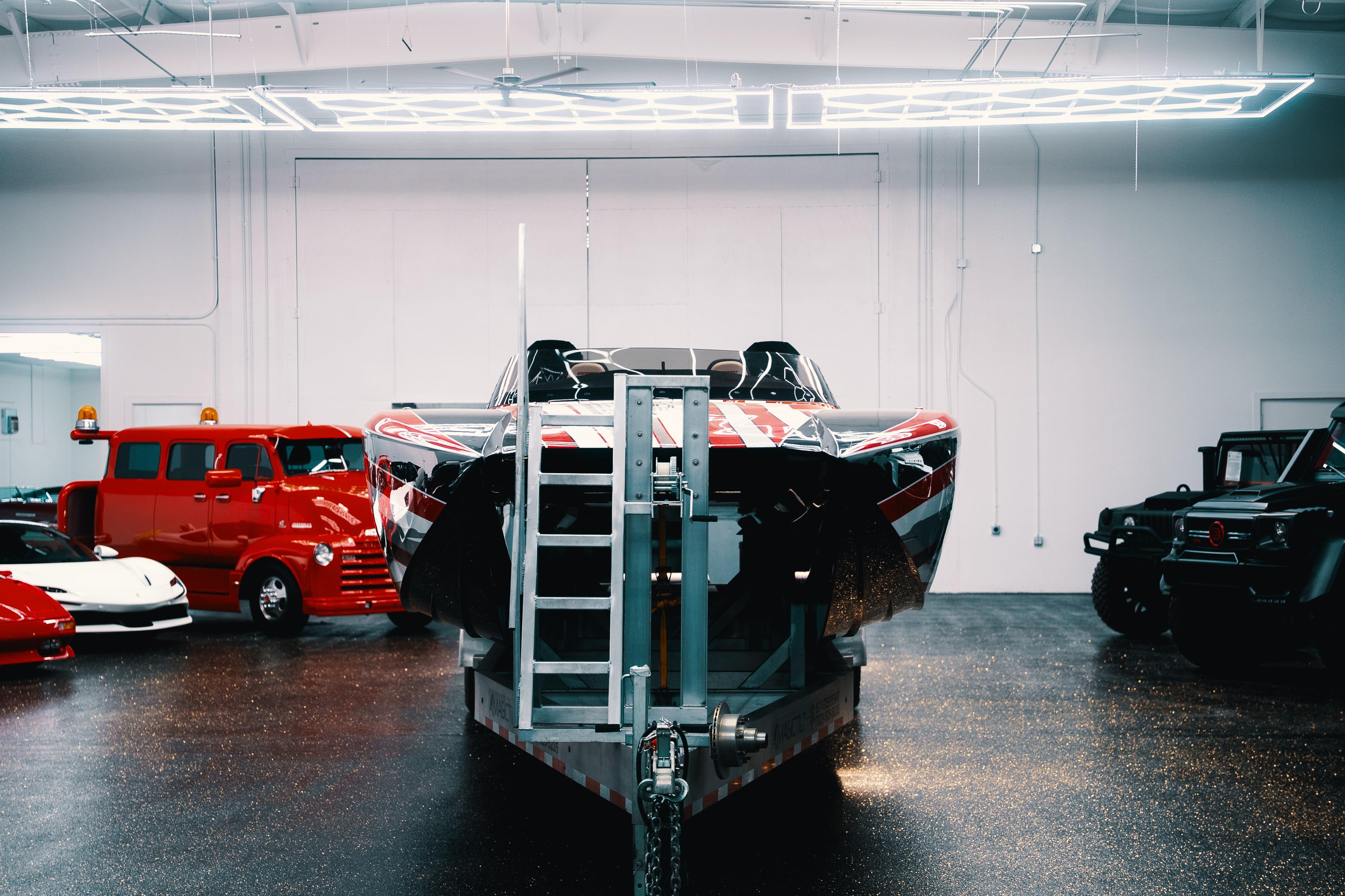 2025 Statement 360 CAT boat in showroom with vintage and luxury vehicles.