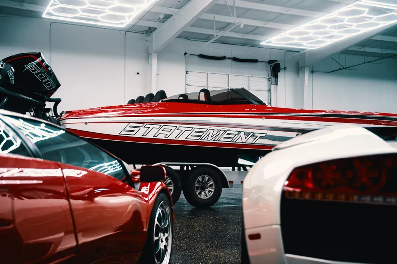  Yacht Photos Pics Red and white Statement 360 CAT boat in showroom, surrounded by luxury cars.