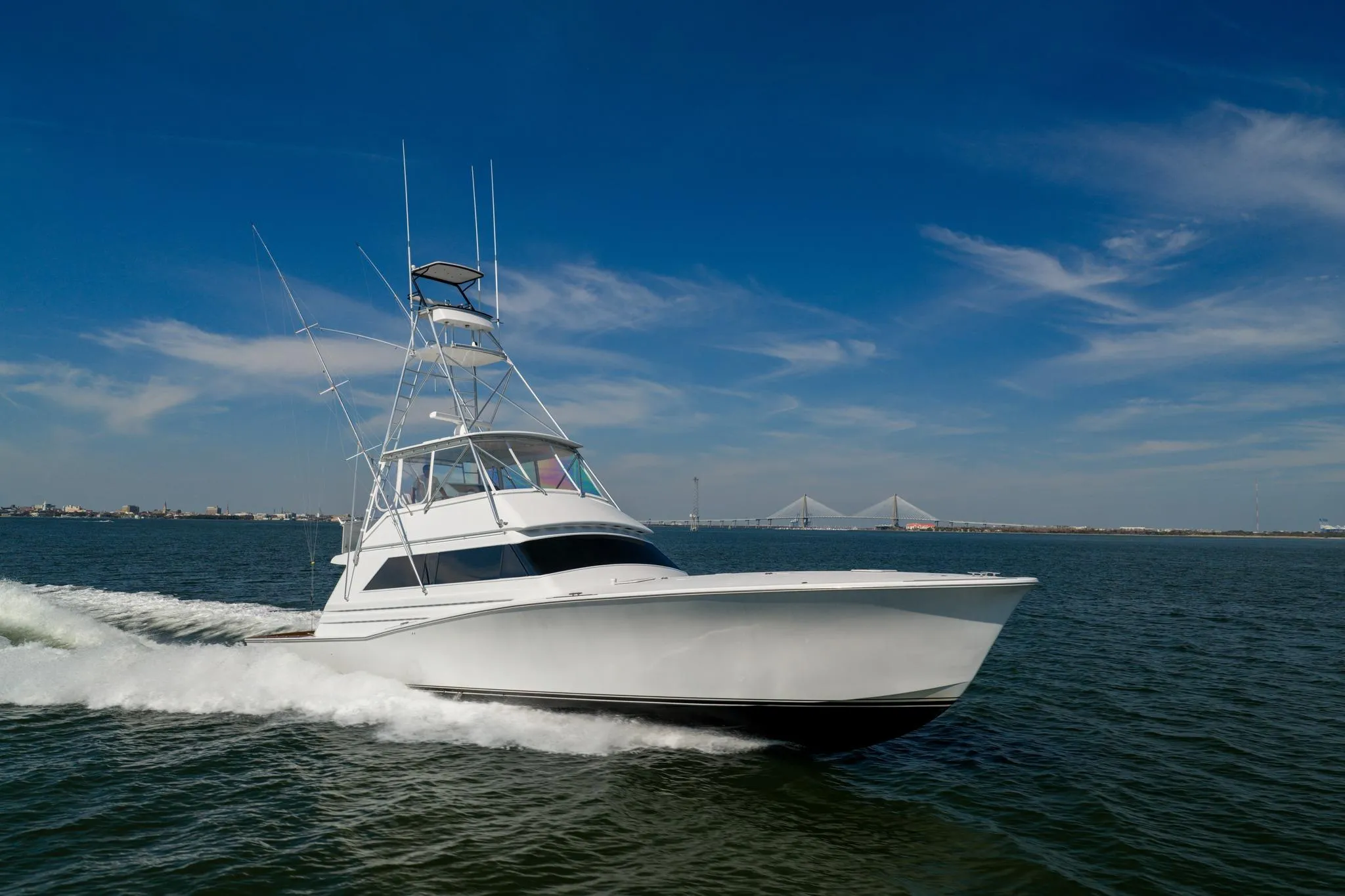 1996 Jim Smith 60 Sportfish yacht cruising on open water under a clear blue sky.