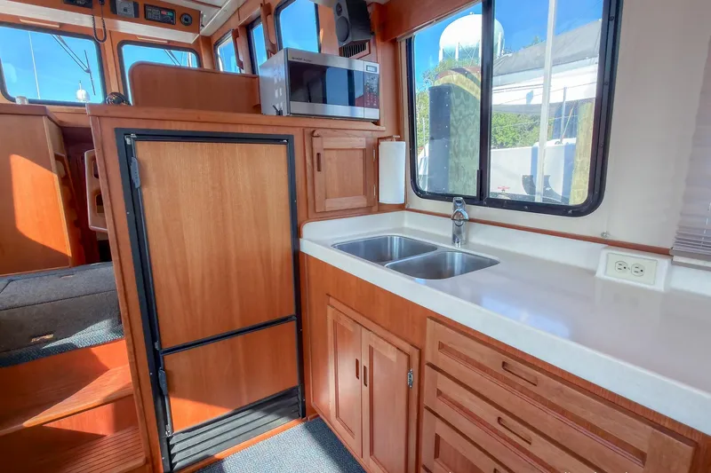 Dee Gee Yacht Photos Pics 1999 Nordic Tug 37 interior kitchen with wooden cabinetry, double sink, and microwave.