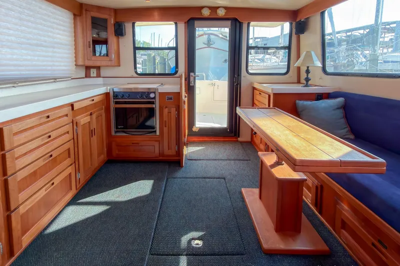 Dee Gee Yacht Photos Pics Interior of a 1999 Nordic Tug 37, featuring wood cabinetry and a cozy seating area.