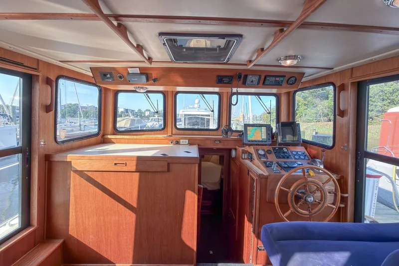 Dee Gee Yacht Photos Pics 1999 Nordic Tug 37 interior with wooden helm, navigation equipment, and large windows.