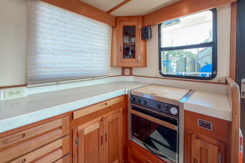 Dee Gee Yacht Photos Pics 1999 Nordic Tug 37 interior kitchen with wooden cabinetry and stove.