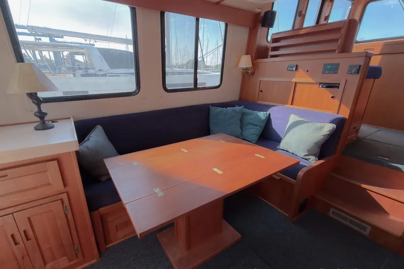 Dee Gee Yacht Photos Pics Cozy interior of a 1999 Nordic Tug 37 with a wooden table and cushioned seating.
