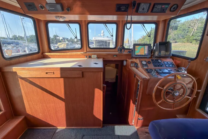 Dee Gee Yacht Photos Pics 1999 Nordic Tug 37 interior with wooden helm, navigation equipment, and large windows.