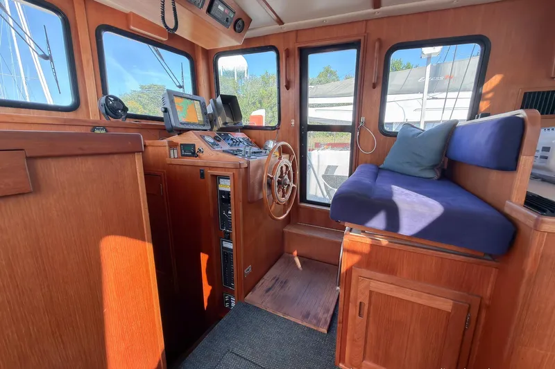 Dee Gee Yacht Photos Pics Cozy 1999 Nordic Tug 37 pilothouse with wooden interior and navigation equipment.