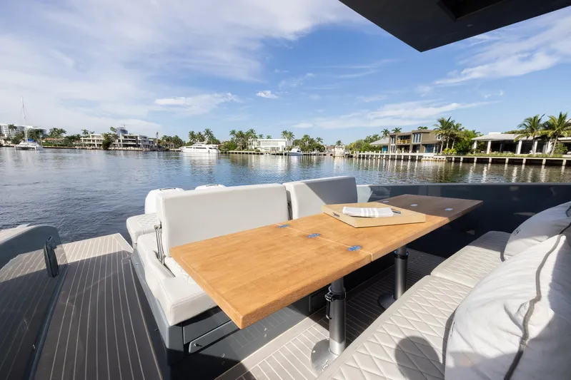 First Class Yacht Photos Pics Tesoro T38 Cruiser 2022 yacht deck with seating and table, overlooking serene waterfront.