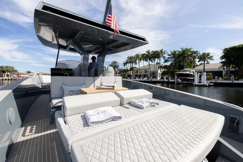 First Class Yacht Photos Pics 2022 Tesoro T38 Cruiser yacht with sunbathing deck, docked by palm trees and waterfront homes.