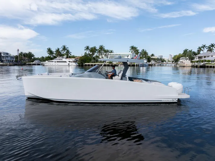 First Class Yacht Photos Pics 2022 Tesoro T38 Cruiser on a calm waterway, surrounded by palm trees and luxury homes.