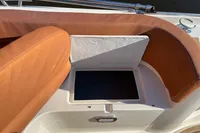 2022 GS 27 boat seating with storage compartment, featuring brown cushions and stainless steel railing.