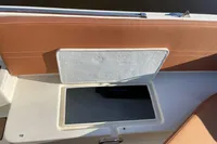 Open storage compartment on a 2022 GS 27 boat with brown seating.