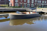 2022 GS 27 boat docked by brick buildings on a sunny day.