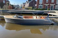 Modern GS 27 boat, 2022 model, docked in a canal near brick houses.