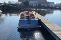 Boat docked by wooden pier, GS 27 model, 2022, calm water, residential background.