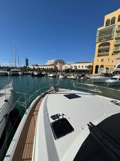 Lady V Yacht Photos Pics 2024 Bavaria Virtess 420 Fly yacht docked in a sunny marina with colorful buildings.