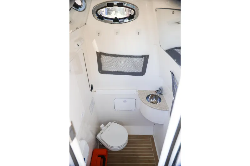  Yacht Photos Pics 2019 Regulator 28 boat interior with compact bathroom, featuring a toilet and sink.