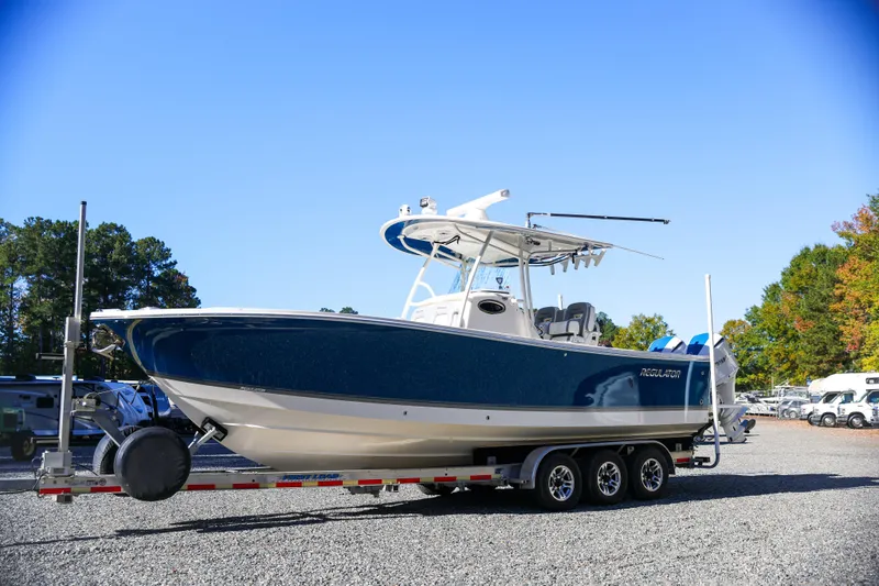  Yacht Photos Pics 2019 Regulator 28 boat on trailer, blue hull, parked outdoors.