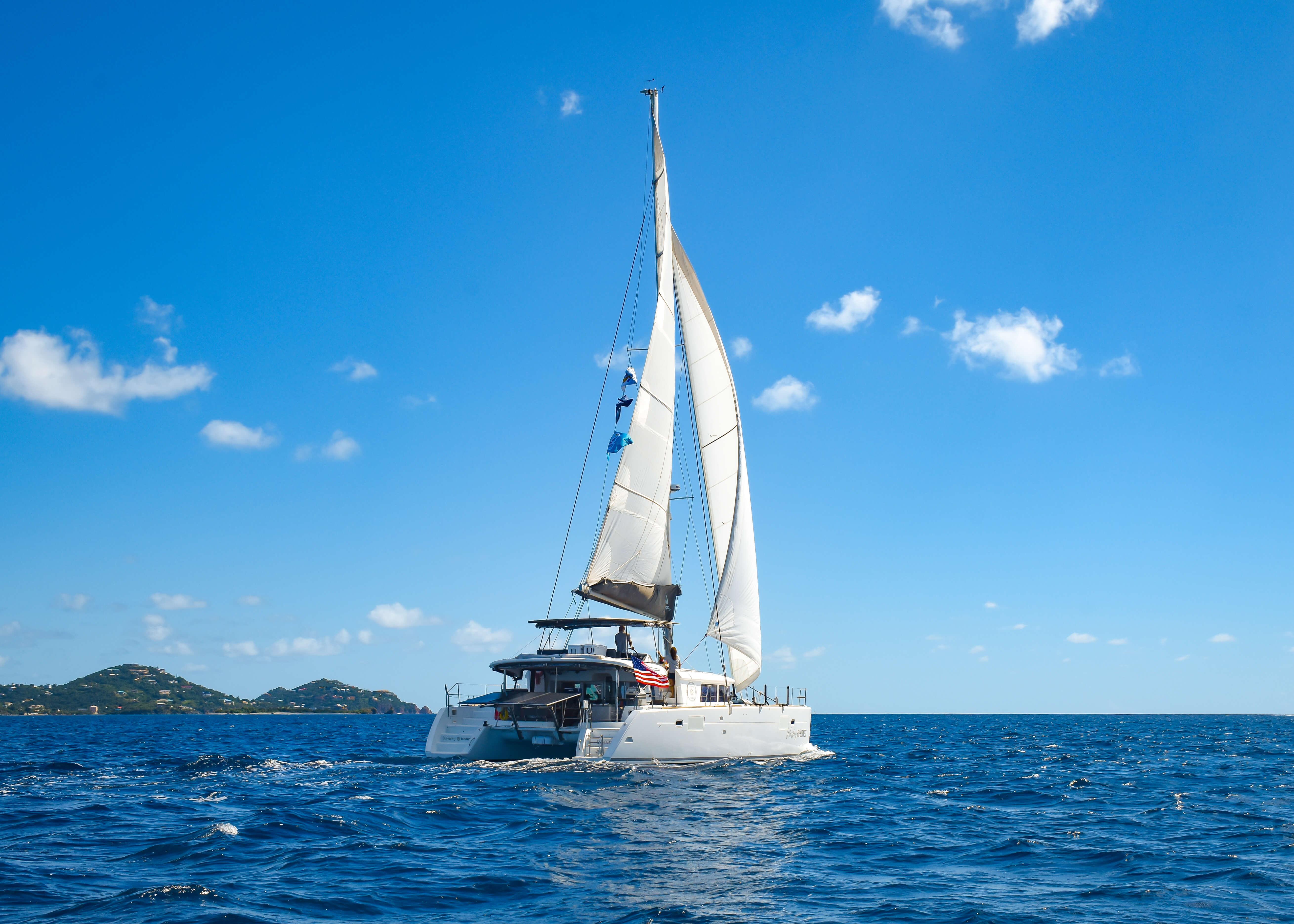 2015 Lagoon 450F catamaran sailing on open sea under clear blue sky.