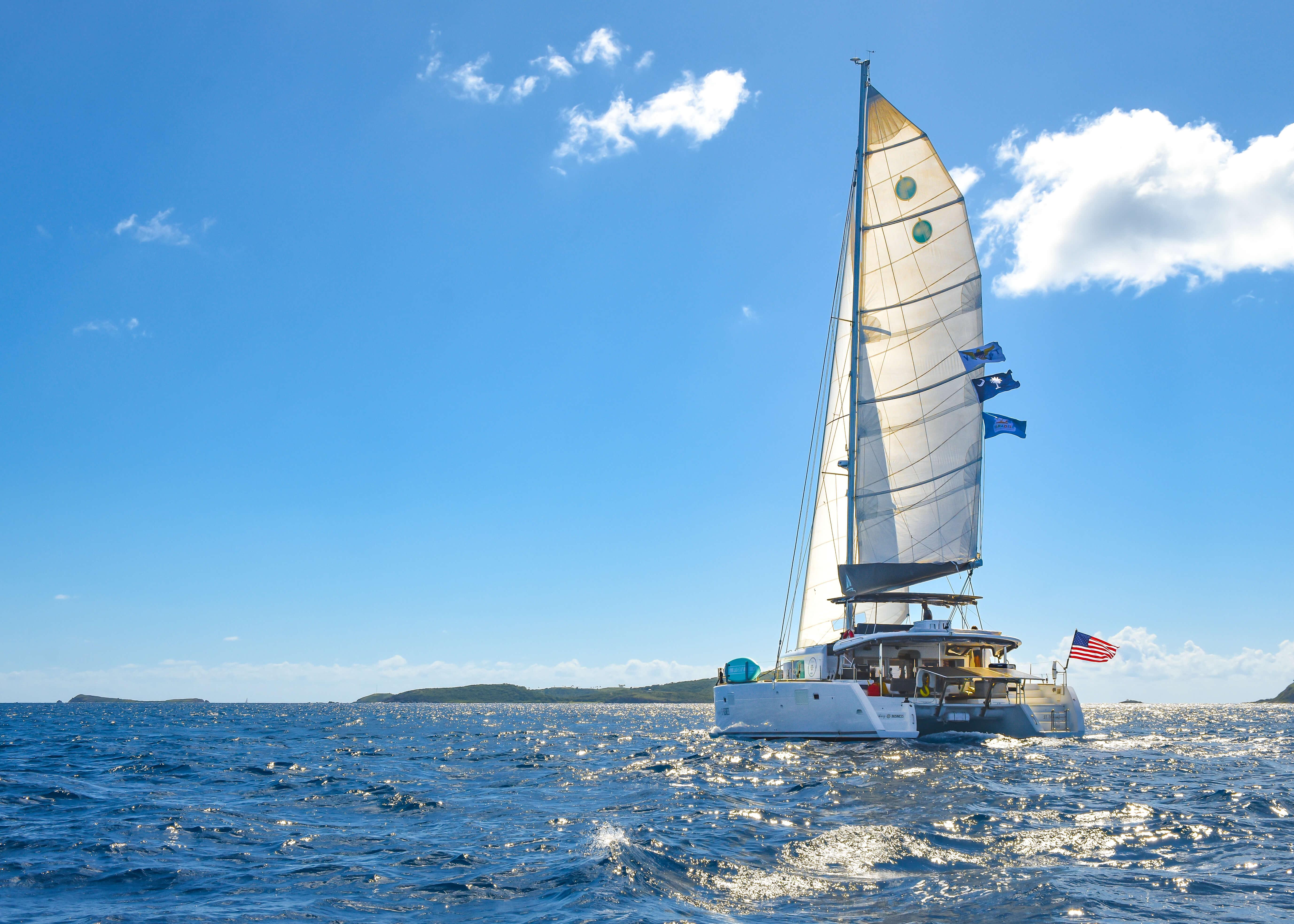 2015 Lagoon 450F catamaran sailing on open sea under clear blue sky.