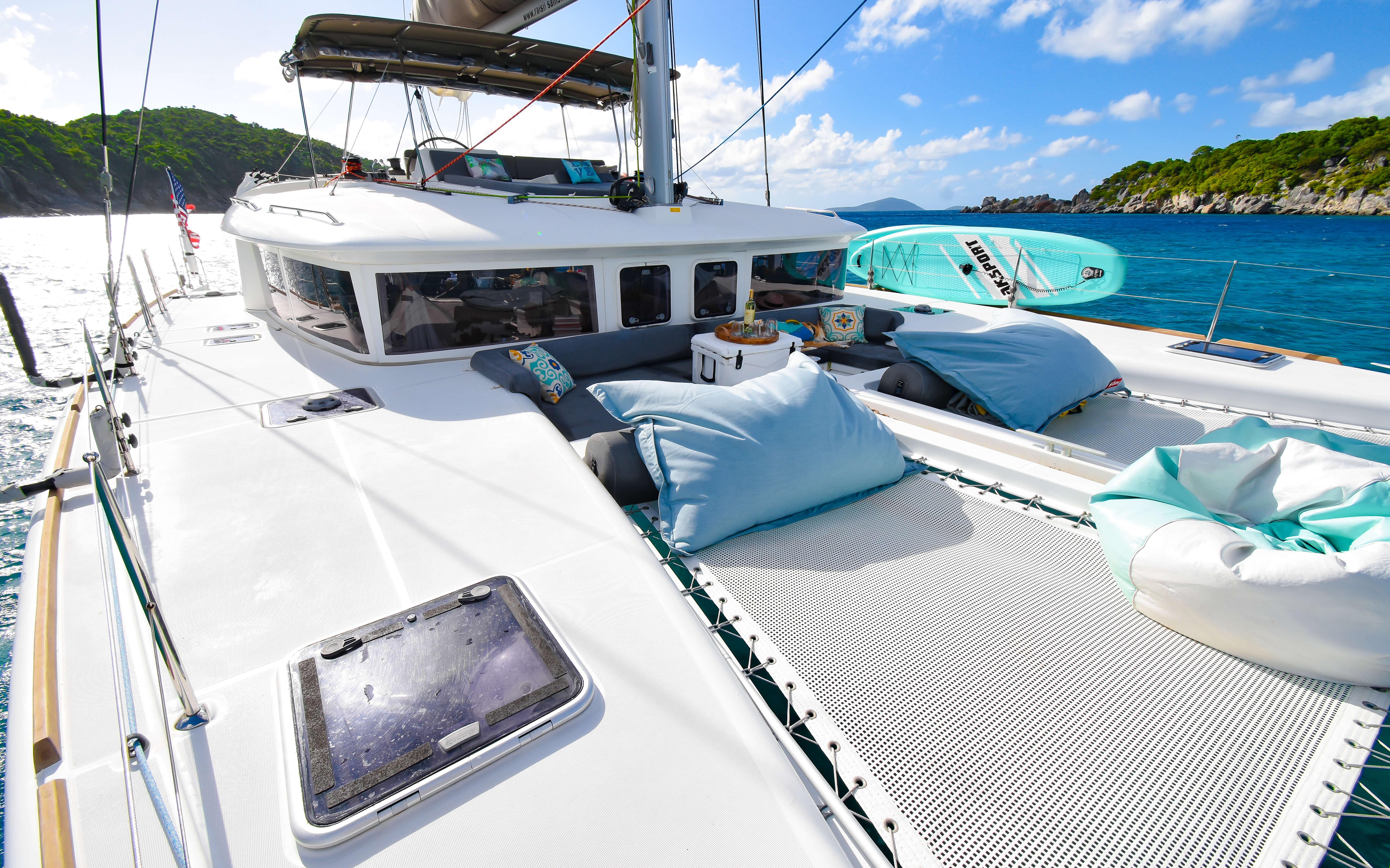 Luxurious 2015 Lagoon 450F catamaran with sunbathing area, sailing in clear blue waters.