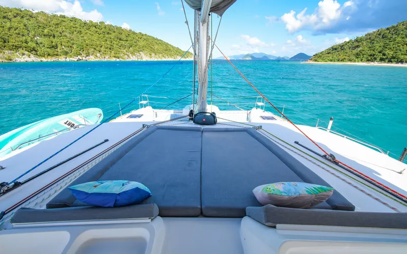 Whiskey Business Yacht Photos Pics Lagoon 450F 2015 catamaran with sunbathing area, turquoise sea, and lush green islands.