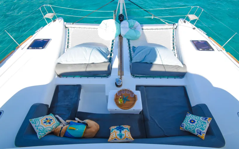 Whiskey Business Yacht Photos Pics Lagoon 450F 2015 catamaran deck with cushions and pillows, overlooking turquoise water.