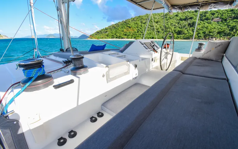Whiskey Business Yacht Photos Pics 2015 Lagoon 450F yacht cockpit with ocean view and lush island backdrop.