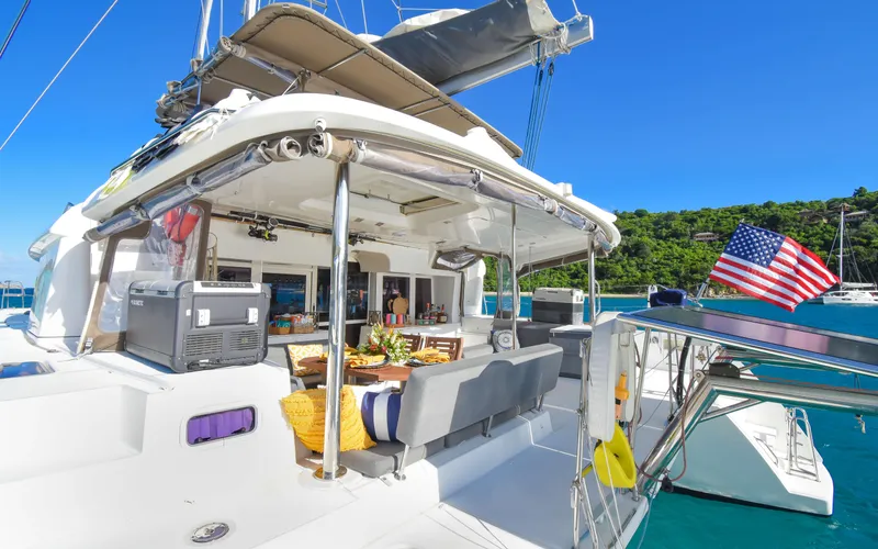 Whiskey Business Yacht Photos Pics Lagoon 450F 2015 catamaran with outdoor seating, American flag, and scenic marina backdrop.
