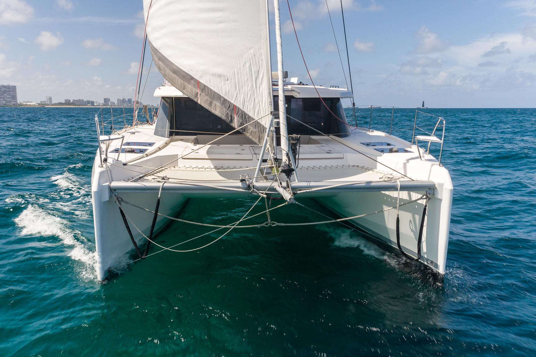 2020 Leopard 45 catamaran sailing on open ocean with city skyline in background.