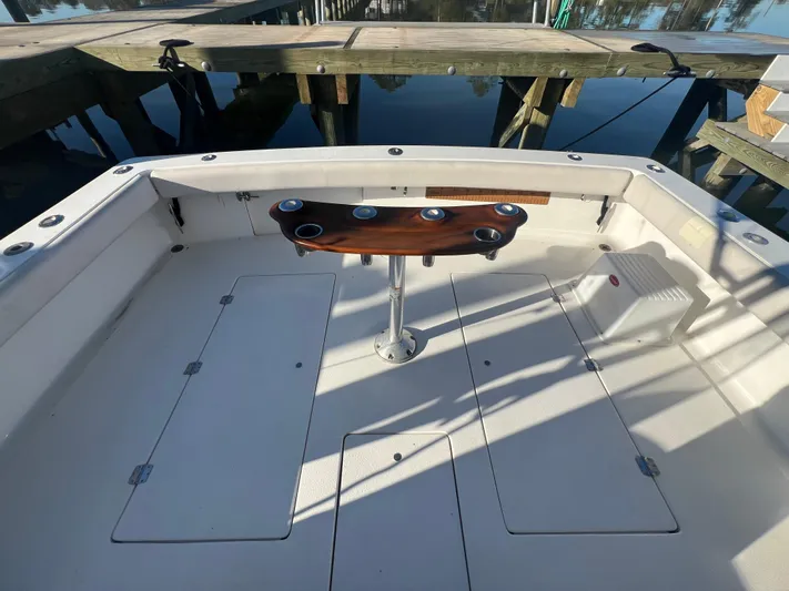 Precedent Yacht Photos Pics 1998 Jersey Cape 36 Express boat deck with wooden table, docked by the water.