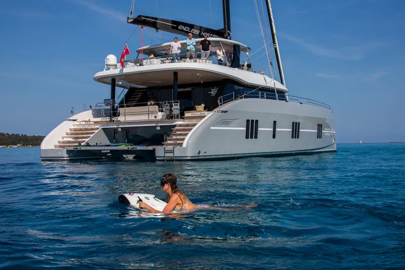 Endless Horizon II Yacht Photos Pics Luxury Sunreef 80 Sail yacht, 2022 model, with person swimming nearby in clear blue water.