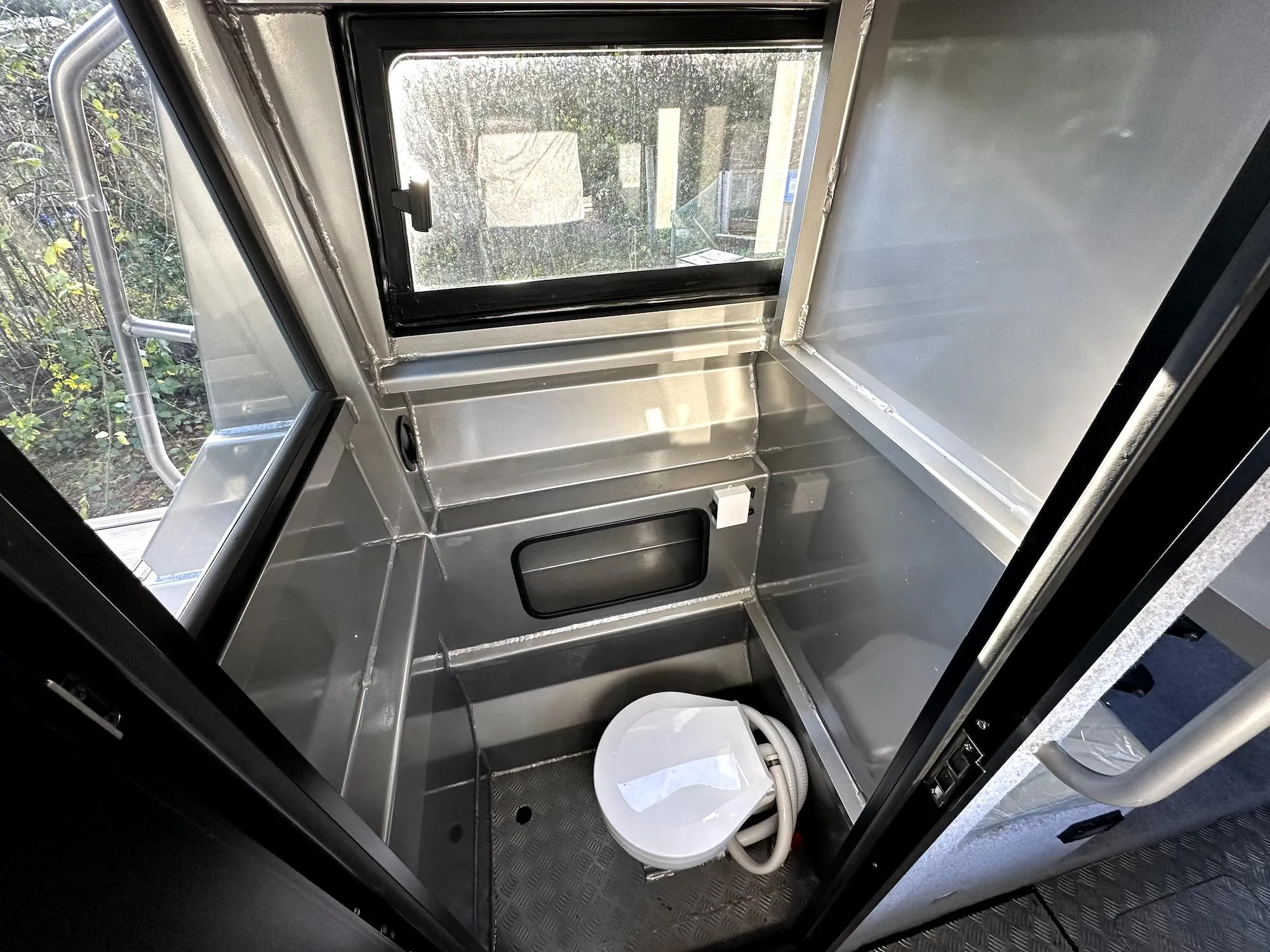 Compact marine bathroom in 2023 Custom Ocean King boat, featuring a toilet and window.