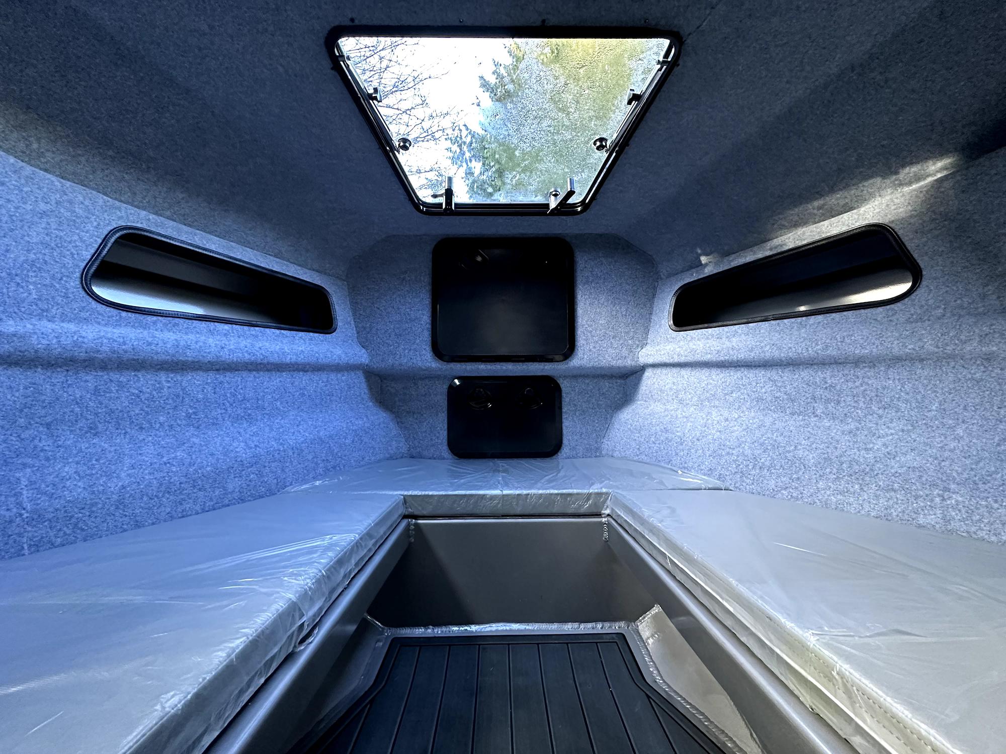 Interior of 2023 Custom Ocean King boat cabin with skylight and cushioned seating.