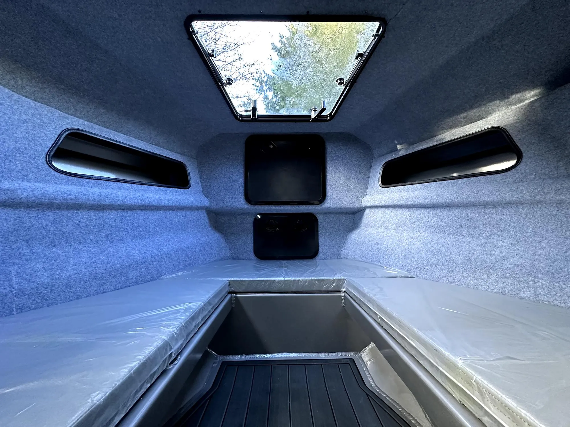 Interior of 2023 Custom Ocean King boat cabin with skylight and cushioned seating.