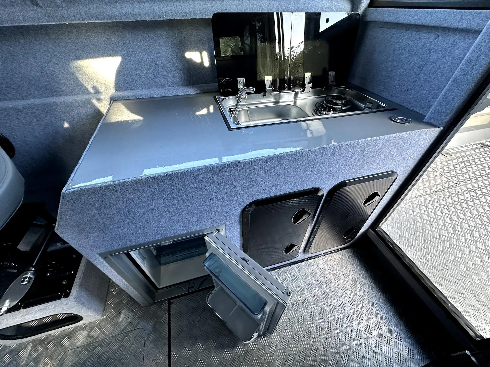 Compact kitchen area in a 2023 Custom Ocean King boat, featuring a sink and storage.