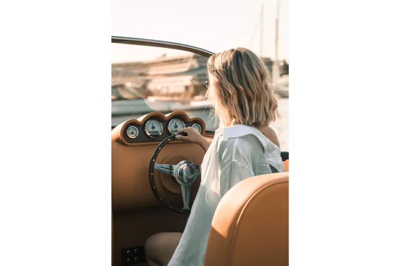  Yacht Photos Pics Woman steering 2025 Seven Seas Yachts Venus Speedster X, 32ft, in a sunny setting.