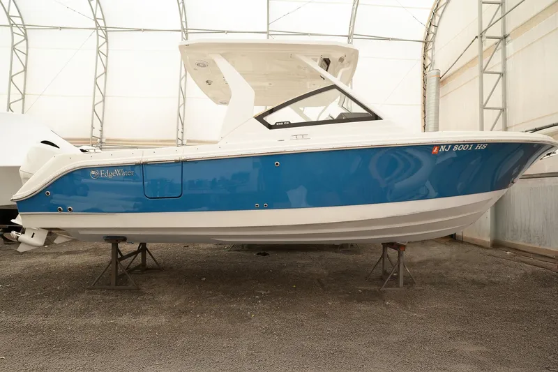  Yacht Photos Pics 2022 Edgewater 262 CX boat in storage, blue and white hull, indoor setting.