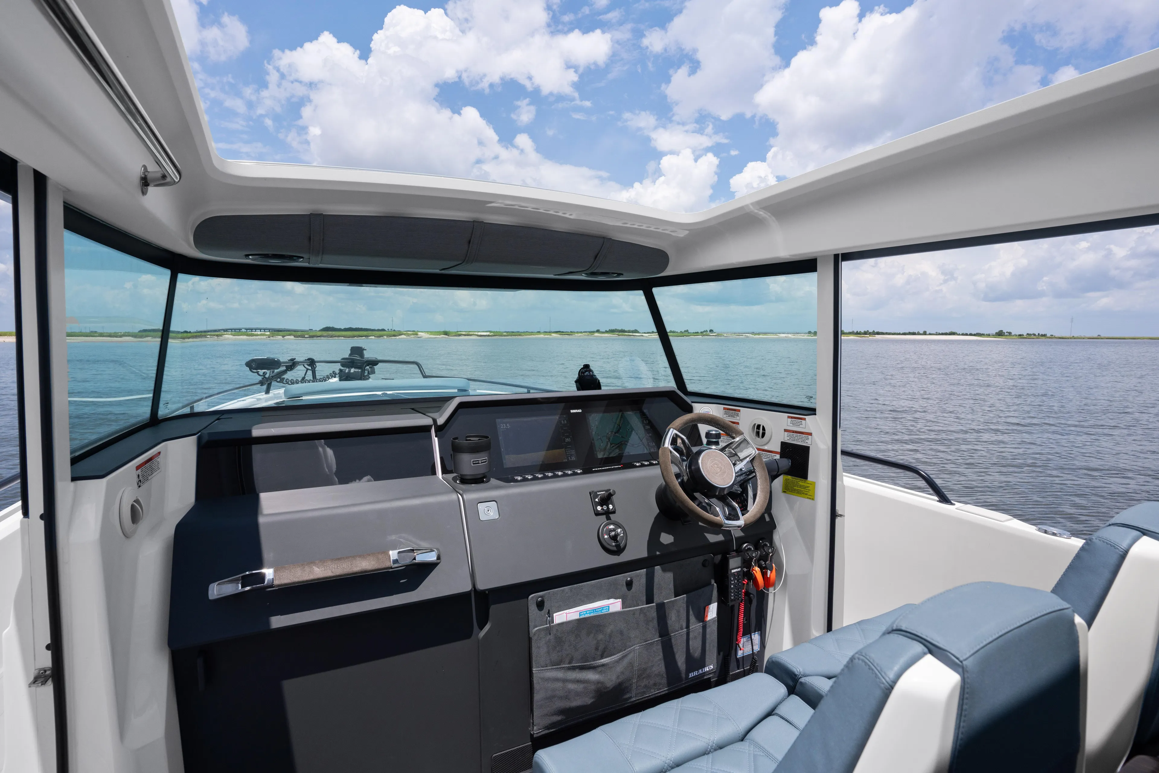 Yacht Photos Pics Interior view of 2023 Axopar 37XC CROSS CABIN, showcasing helm and seating with ocean backdrop.