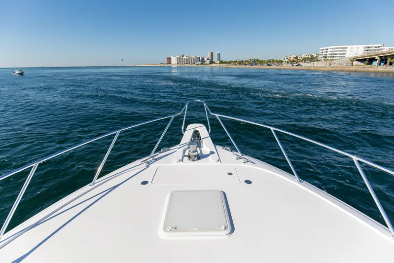 Blacksmith Yacht Photos Pics Bow view of 2008 Hatteras 60 Convertible yacht cruising near coastal cityscape.