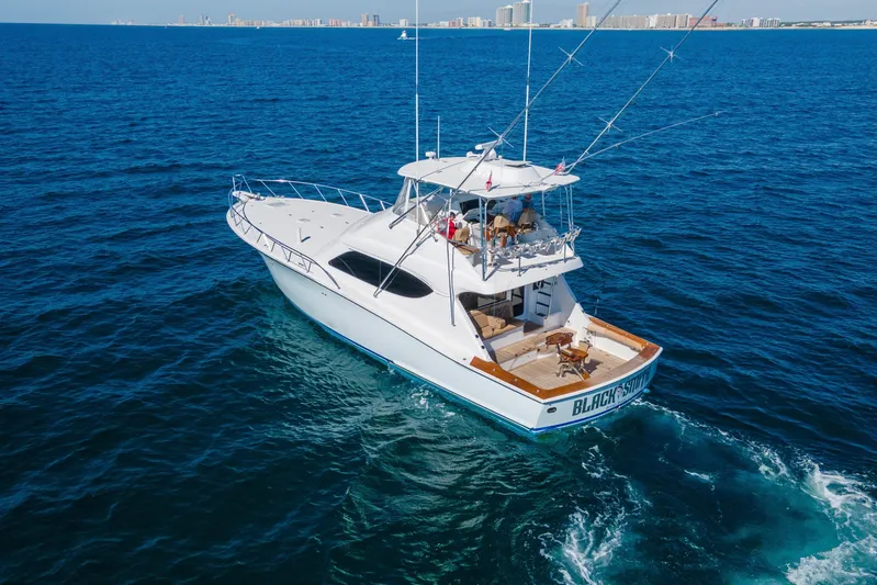 Blacksmith Yacht Photos Pics 2008 Hatteras 60 Convertible yacht cruising on open blue sea, city skyline in background.