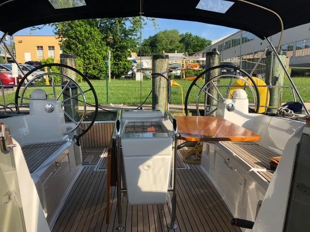 Serendipity Yacht Photos Pics Cockpit of 2014 Jeanneau Sun Odyssey 469 sailboat with dual steering wheels and wooden table.